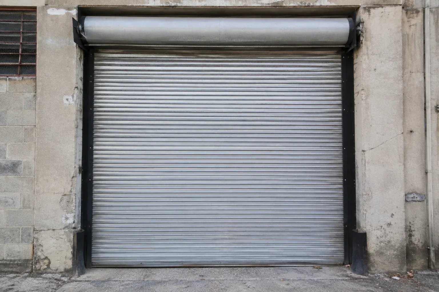 Closed metal rolling shutter in a weathered warehouse opening. — Commercial Rolling Door Repair, Hamilton